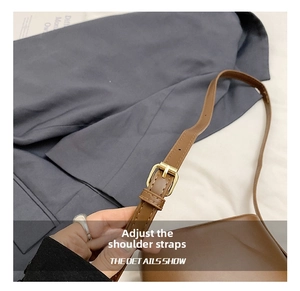Detail of adjustable brown leather shoulder strap with golden buckle and stitching