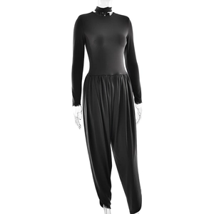 Front view of a sleek black backless jumpsuit with side slits on a clear mannequin