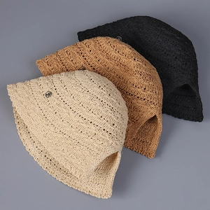 Close-up of knit straw bucket hats in cream, khaki and black with metallic round accents