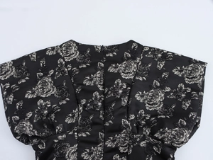 Detail of black jacquard fabric with silver floral pattern and rear zipper closure