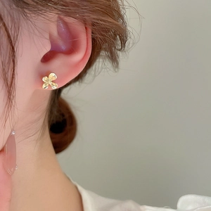 Gros plan d'élégantes boucles d'oreilles trèfle doré portées par un mannequin