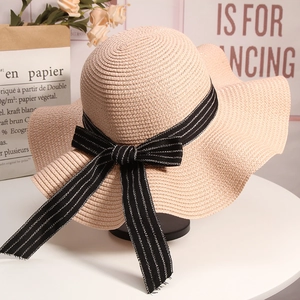 Macro view of wide brim straw sun hat with black and white striped ribbon detailing