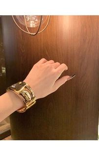 Nahaufnahme des breiten goldenen Armreifs mit unregelmäßiger Hammerschlag-Textur und Glanz