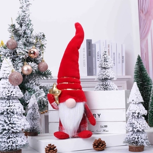 Christmas gnome plush with red sequin hat and gold star ornament on white fence