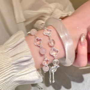 Detail of layered pink clover charm bracelets and translucent bangle on a woman's wrist