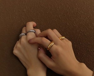 Close-up of vintage wave textured rings in gold and silver finish on a hand