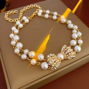 Detail of double-layer pearl bracelet with golden crystal bow clasp on display stand