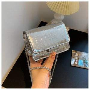 Detail of silver crocodile-embossed mini square bag with shiny metallic texture and chain