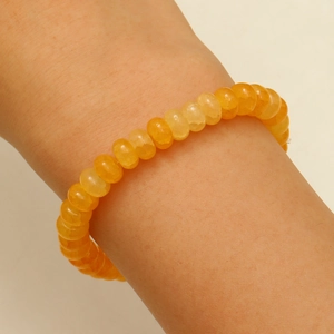 Vue détaillée d'un bracelet en perles jaune-orange au poignet avec des perles abaque