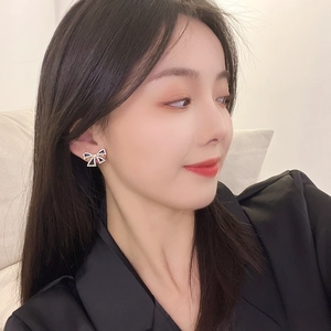 Close-up of elegant S925 black bow earrings with sparkling crystals worn by a model