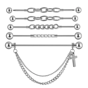 Macro view of industrial barbells with cross pendant and crystal stones for ear piercing
