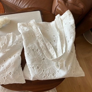 Detail of white cotton eyelet lace embroidery on tote bag with matching pouch