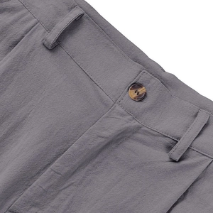 Dettaglio dei pantaloni in lino grigio scuro con chiusura a bottone e doppie cuciture