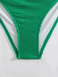 Detail view of emerald green smocked bikini bottoms with crinkled texture and white mesh lining