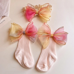 Detail of baby socks and lace headband with gradient organza bows and gold trim