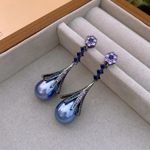 Detail view of vintage blue teardrop pearl earrings with purple crystal flower accents