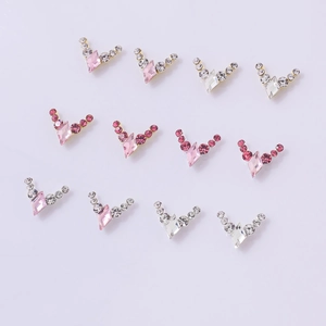 Macro detail of V-shaped nail charms with pink diamond crystals and sparkling rhinestones