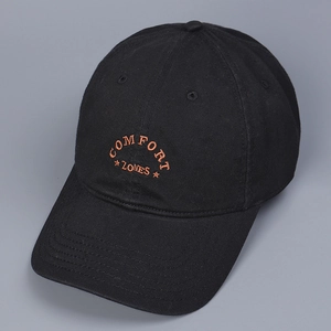 Detail of embroidered COMFORT ZONES lettering on a black cotton baseball cap