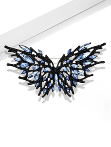Macro detail of dark butterfly brooch with blue crystals and black branch-like metal frame