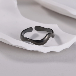Minimalist black wavy open ring in titanium steel on a white decorative tray
