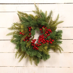 Christmas wreath with green pine needles and red berries on a rustic white wood background