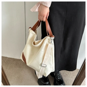 Detail of canvas tote bag with brown leather handles and adjustable shoulder strap worn by model