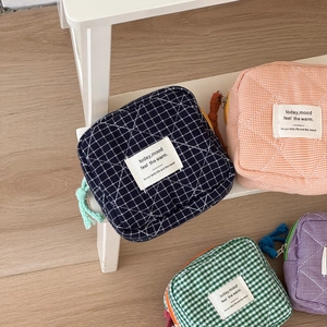Detailed view of quilted plaid storage pouches with soft cotton texture and colorful zippers
