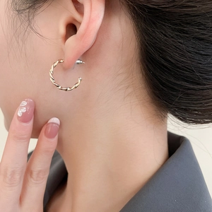 Detailansicht einer Frau mit goldenen gedrehten Creolen im minimalistischen C-Form Design