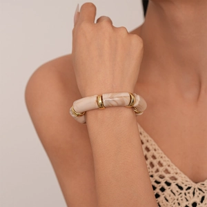 Detail of acrylic bamboo-style stretch bracelet with marble texture and gold ring spacers