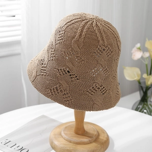Detailed view of the khaki woven bucket hat featuring hollow knit patterns on a wood stand