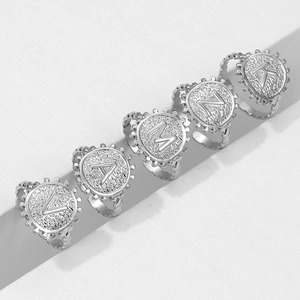 Detailed view of silver titanium steel rings with textured letters V A M N K on grey steps