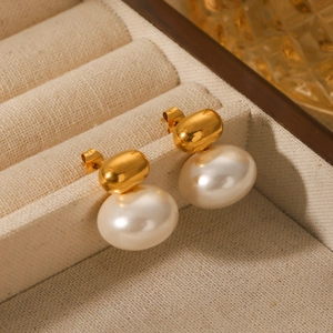 French vintage pearl drop earrings with golden metal beans on beige linen tray