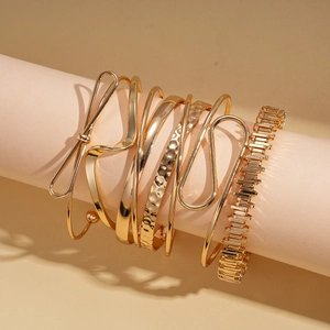 Six-piece set of gold geometric twisted open bangles with metallic finish and bow design