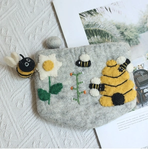 Detailed embroidery of bees and honeycombs on a handmade grey wool felt coin purse