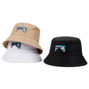 Close-up of embroidered mountain patch on khaki, white, and black cotton bucket hats
