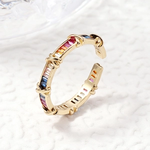 Macro detail of gold open ring featuring rainbow baguette-cut gemstones and twisted metal