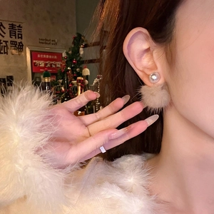 Elegant pearl and beige plush pom pom earrings worn by a model in a cozy winter setting
