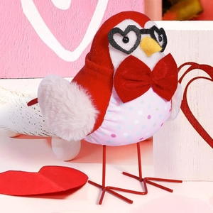 Close-up of cute Valentine bird figurine with heart glasses on pink wooden background