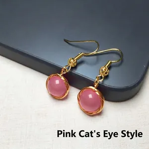 Vue détaillée de boucles d'oreilles en œil de chat rose et fil d'or 14K fait main