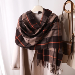 Detail of soft plaid scarf with fringe in brown and beige draped over a coat