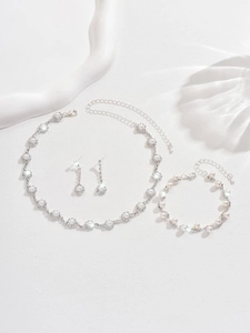 Detailed close-up of bridal jewelry set with pearls and rhinestones on white background