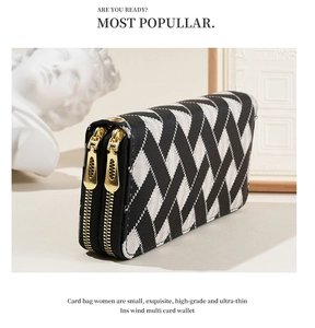 Detailed view of women's black and white striped wallet with dual gold zippers
