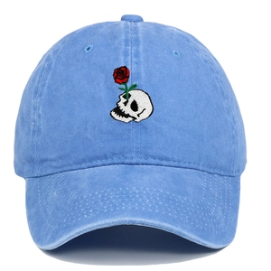 Detail of embroidered skull and red rose on vintage blue washed denim baseball cap