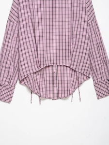 Détail de la chemise à carreaux rose et marron avec ourlet asymétrique et poignets boutonnés
