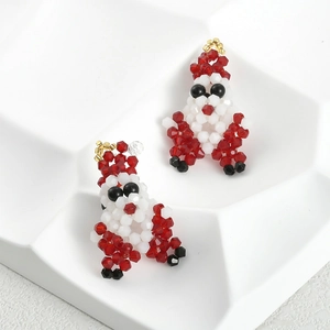 Detailed view of handmade beaded Santa Claus earrings on a white geometric display tray