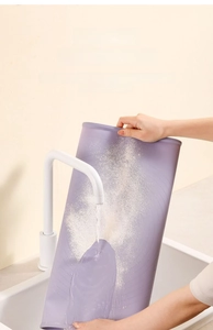 Detail showing water rinsing flour off a non-stick purple silicone baking mat in a sink