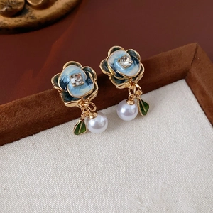 Detailed view of blue enamel flower earrings with sparkling crystals and white pearls