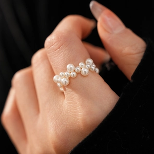 Nahaufnahme eines gewebten weißen Perlenrings mit elegantem Glanz an einem Modellfinger