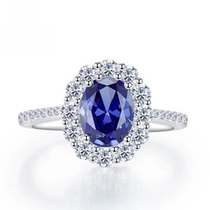 Macro shot of oval blue sapphire ring with sparkling diamond halo in silver setting