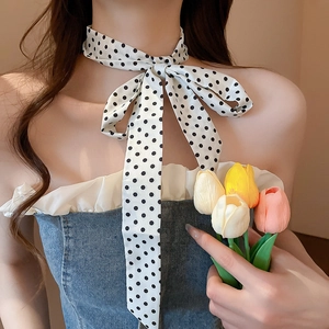 Close-up of elegant black and white polka dot silk scarf tied in a bow on the neck